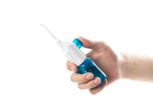 The hand holds the dental irrigator. Close up. Isolated on a white background.