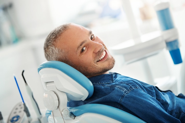 man sitting in dental chair smiling at the camera