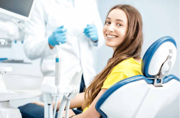 woman with toothy smile sitting at the dental chair w