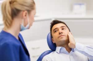 male patient with toothache complaining to female dentist at dental clinic office