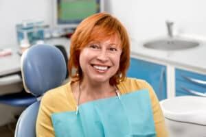 Red-headed mature woman at the dentist is pleased with gentle dental care