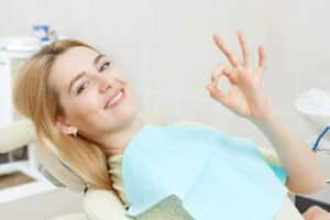Dental patient flashes the OK sign, indicating that she is feeling comfortable despite typically having anxiety