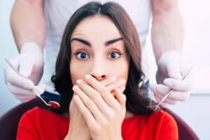 Woman covers her mouth, afraid of having dental work done because of gag reflex.